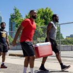 Three people carrying a cooler