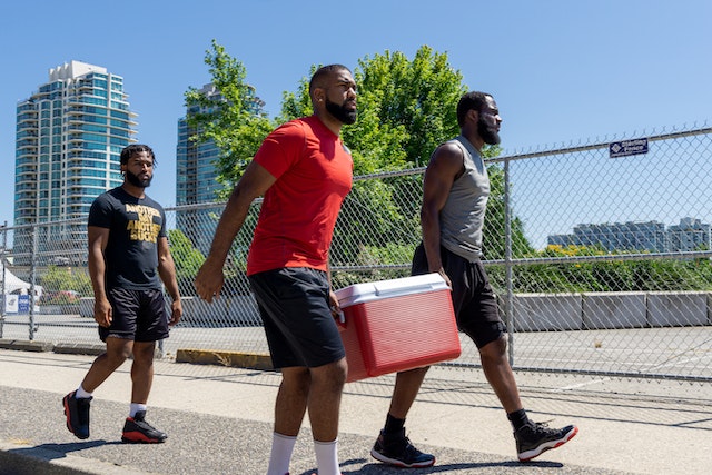 Three people carrying a cooler