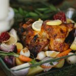 roasted chicken with vegetables in glass roaster on table with fir sprigs