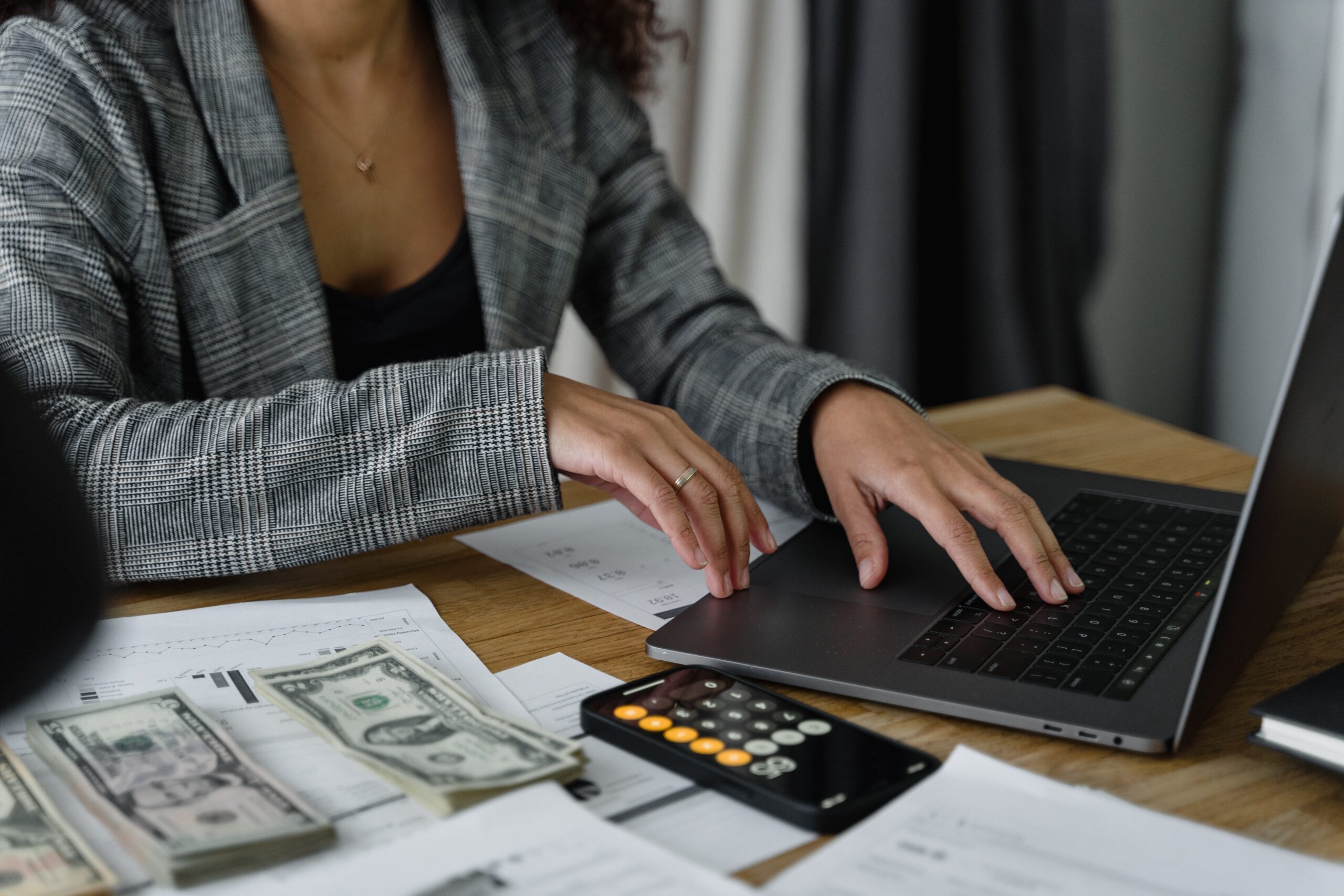 Woman sitting at desk with laptop, papers, and calculator.