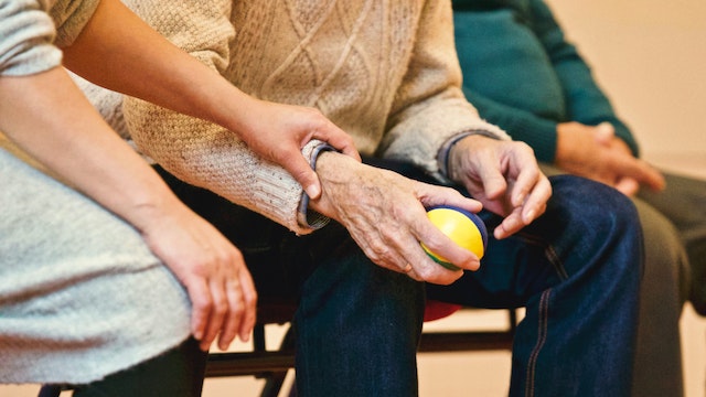 A person helping a senior at an assisted living facility