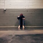 Person sitting on the floor with their knees up and their head resting on top.