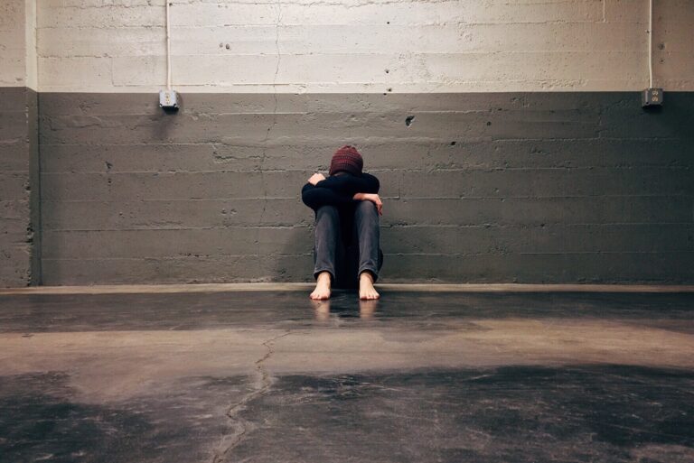 Person sitting on the floor with their knees up and their head resting on top.