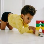 a boy in yellow sweater playing on the floor