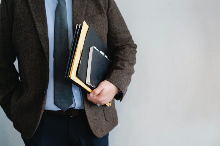 Professional man standing with binders and notebooks in his hands.