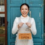 Woman standing outside of a business holding an open sign.