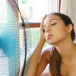 A woman cooling off in front of a fan
