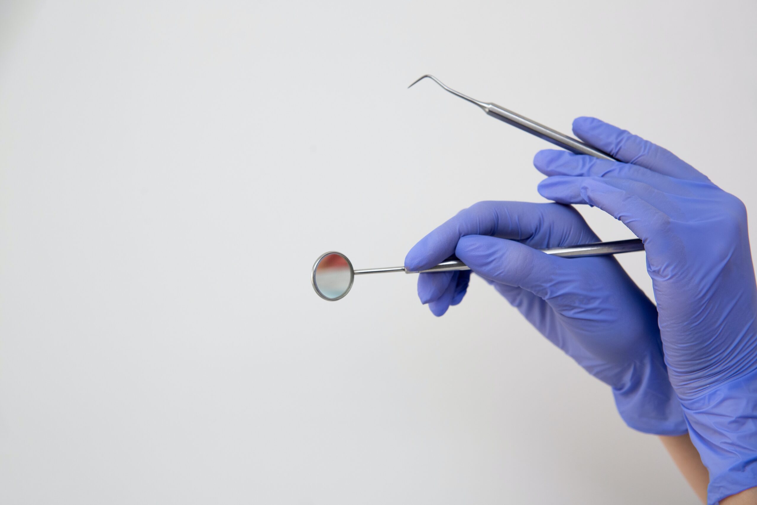 Close-up shot of person's hands who is wearing gloves and holding dental cleaning tools.