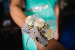Someone displaying their corsage to the viewer, dressed for a formal dance.