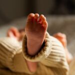 foot of unrecognizable newborn baby lying in crib