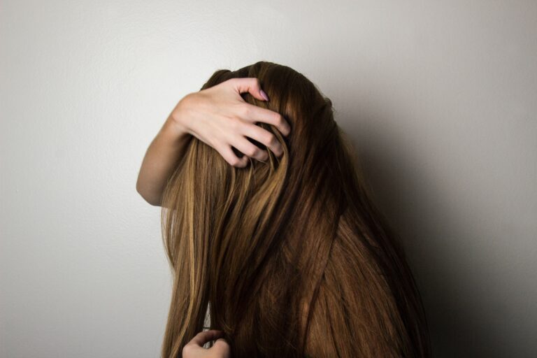Woman facing away from the camera with her hands in her hair.