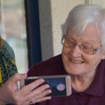 An elderly woman looking at a picture on another woman's phone