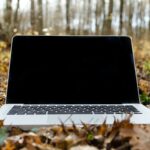 silver macbook pro with black screen on withered leaves