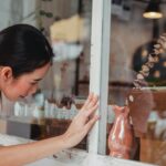 asian woman touching showcase of shop with decorative items