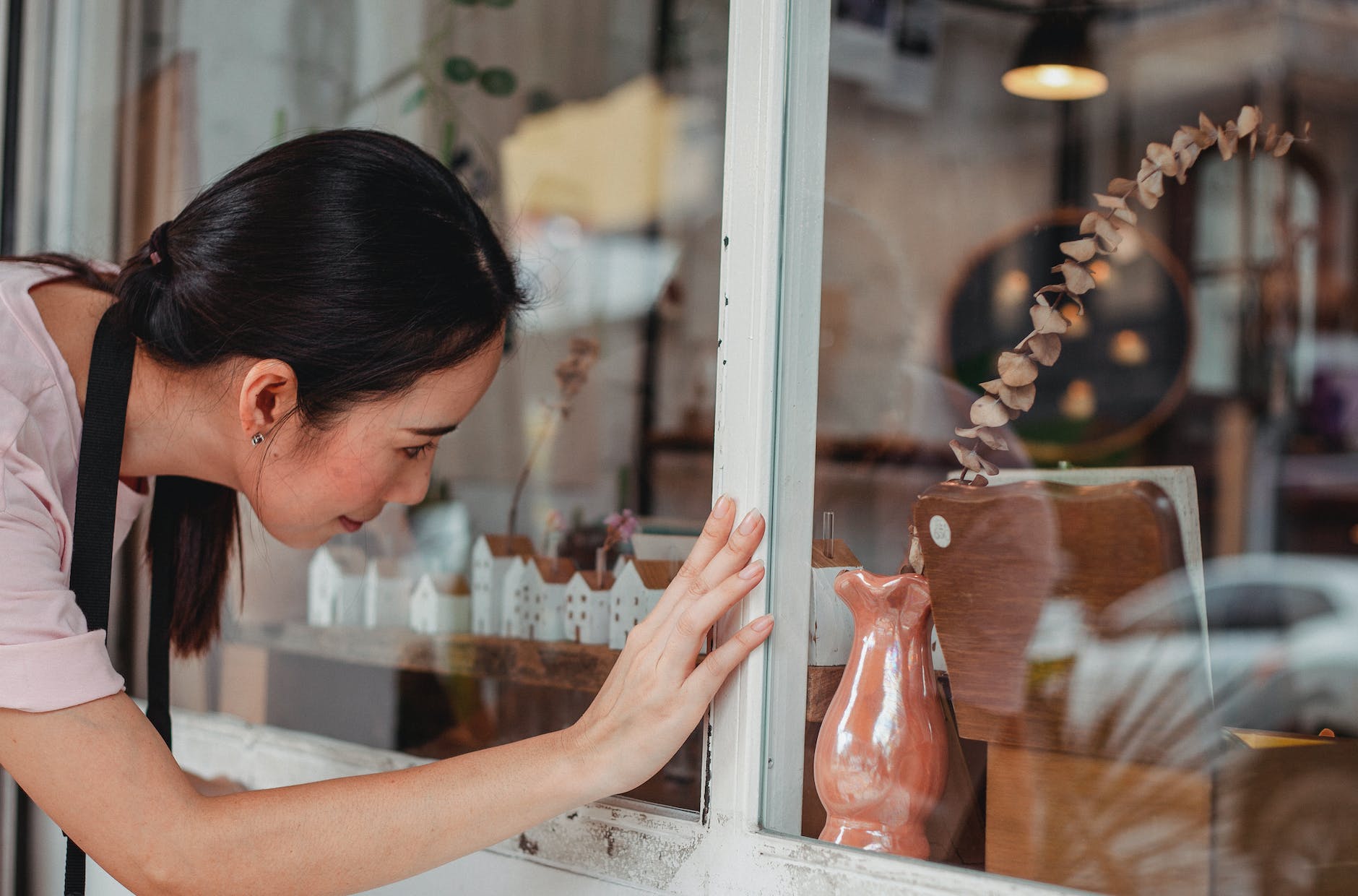 asian woman touching showcase of shop with decorative items