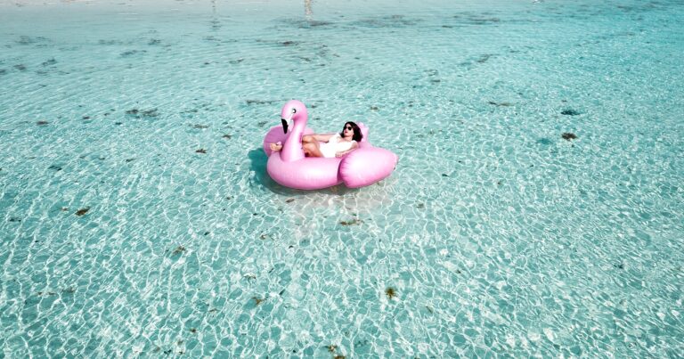Person floating on a flamingo blow-up in the ocean.