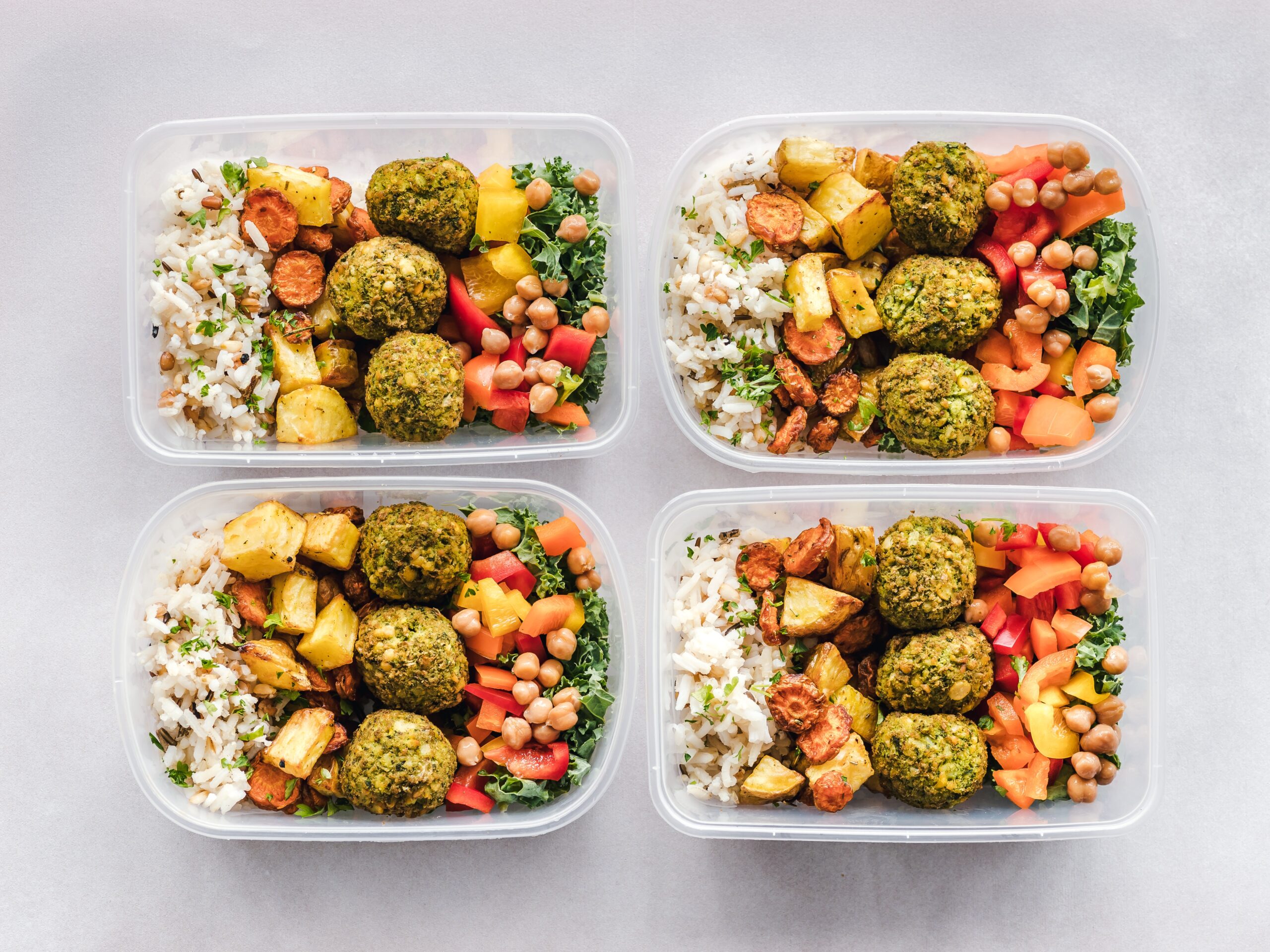 Four containers filled with food on a counter.