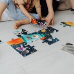 Kids sitting on the floor putting a puzzle together.
