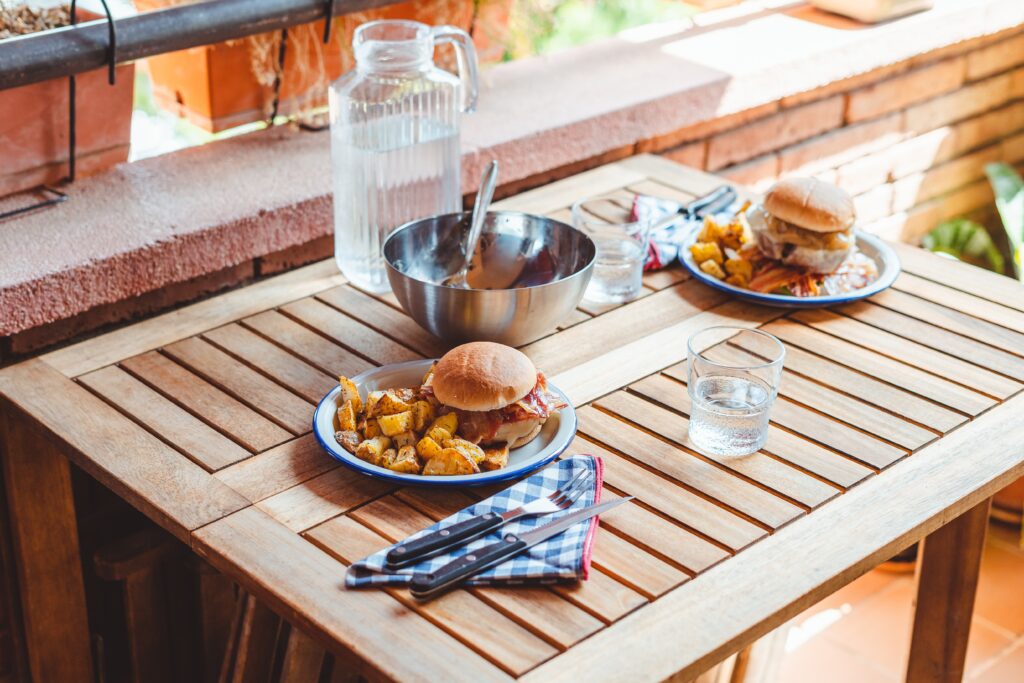 Outdoor table with plates of food on top.