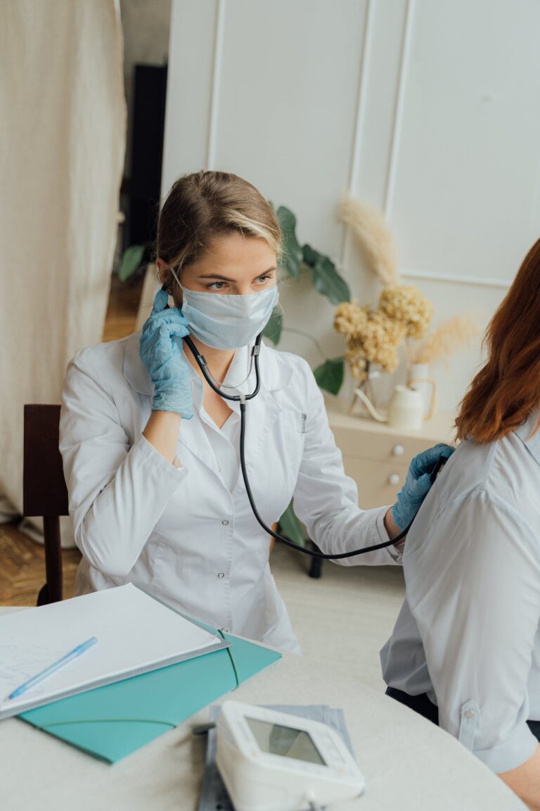 A masked doctor using a stethoscope to listen for a patient's breathing