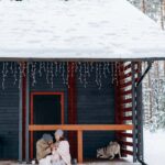 A young family sitting on the porch of a snow-covered home, enjoying the day.