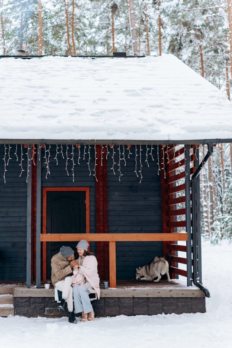 A young family sitting on the porch of a snow-covered home, enjoying the day.