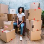 photograph of a woman in a white shirt sitting beside cardboard boxes