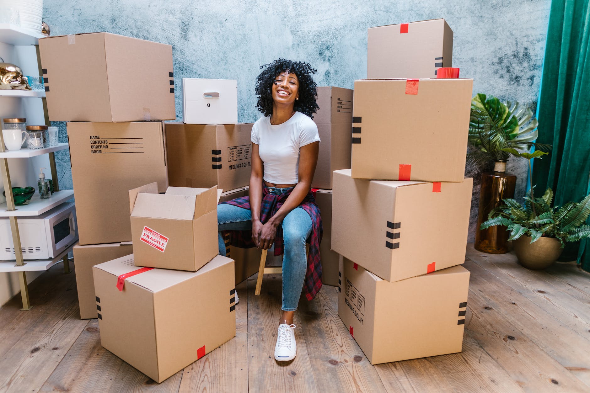 photograph of a woman in a white shirt sitting beside cardboard boxes