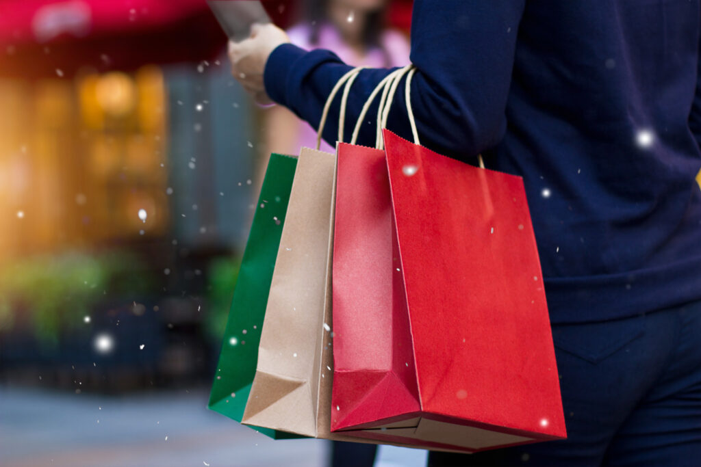 Christmas shopping - shopping bags in hand with snowflake on christmas decoration and lighting on street background