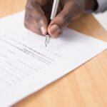 A hand holding a pen signing a document