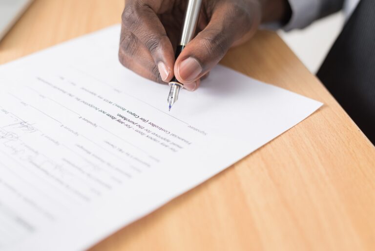 A hand holding a pen signing a document