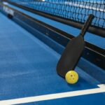A pickleball paddle and ball on the court