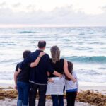 A family standing arm in arm at the seashore.