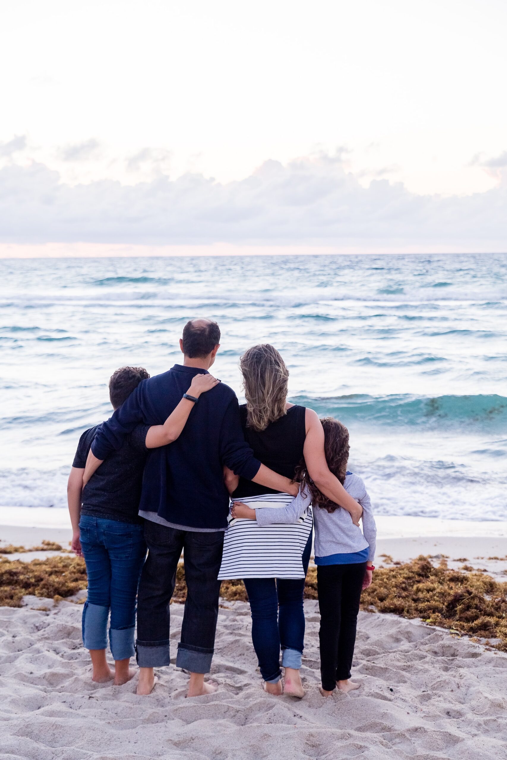 A family standing arm in arm at the seashore.