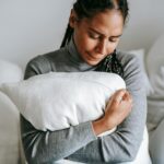 A woman hugging a pillow, clearly in distress.