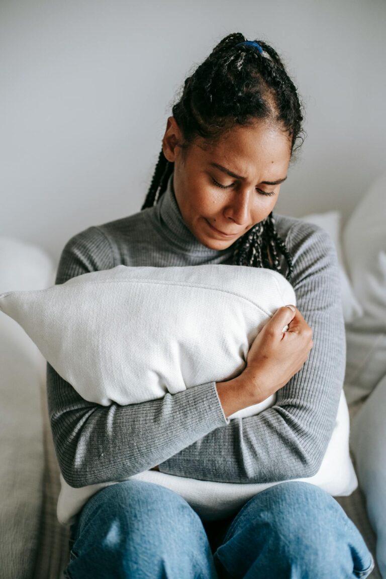 A woman hugging a pillow, clearly in distress.