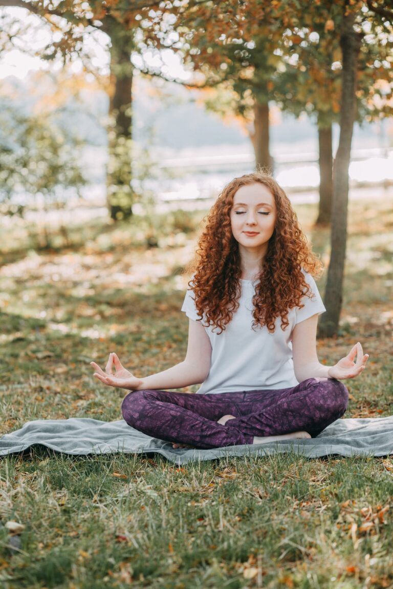 A woman seated in a park meditating