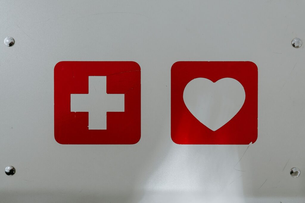 A white cross and white heart each cut out of a red square