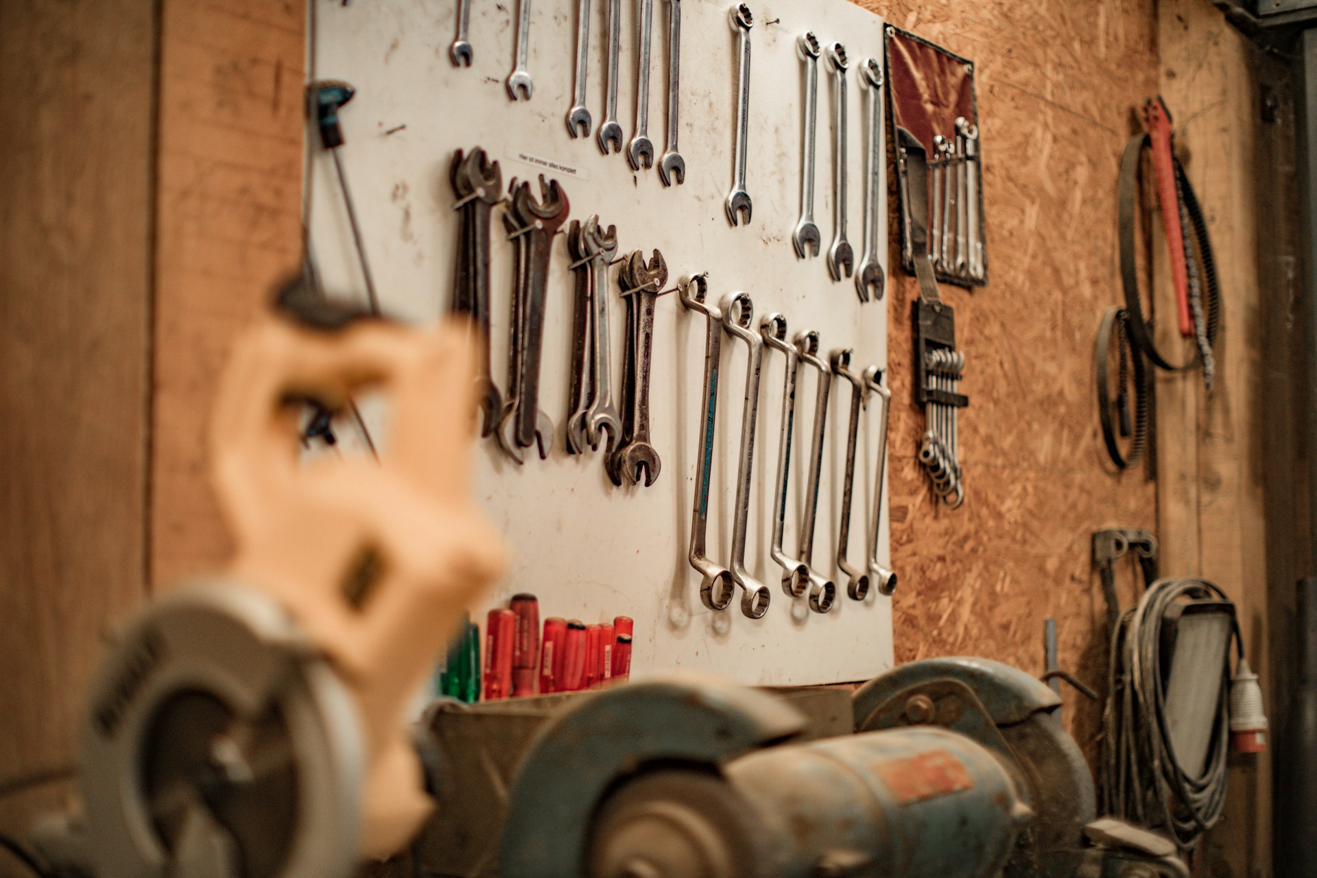 A pegboard with various wrenches hanging above a workbench in a garage