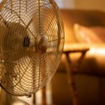 A close up of a standing fan placed in a room.