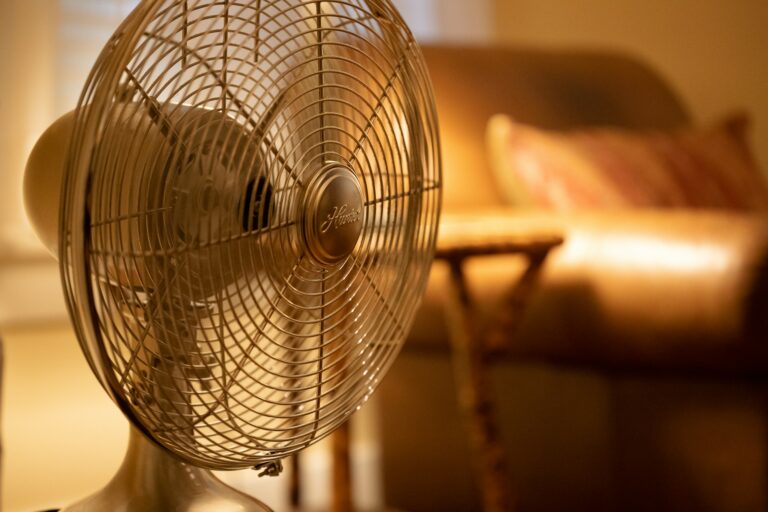 A close up of a standing fan placed in a room.