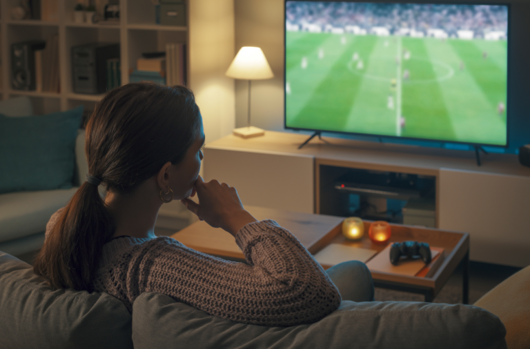 A lady watching football on TV alone at home.