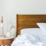 Side of the bed with a lamp and table.