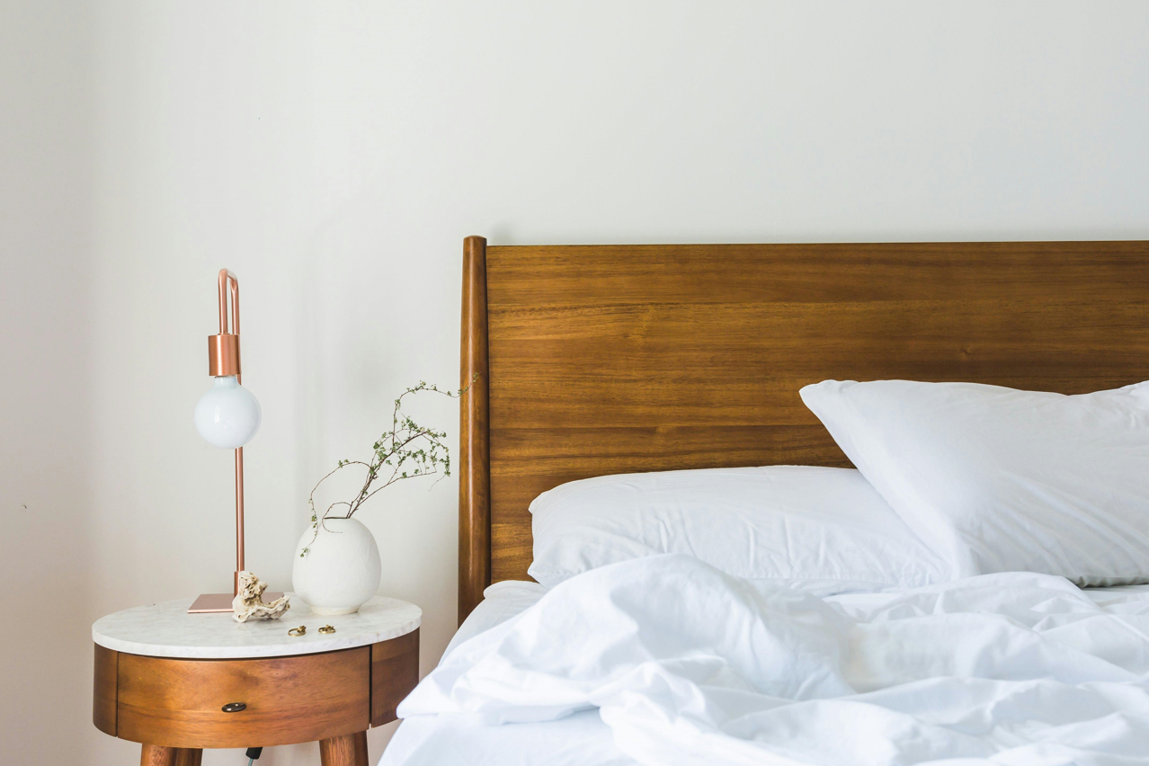 Side of the bed with a lamp and table.