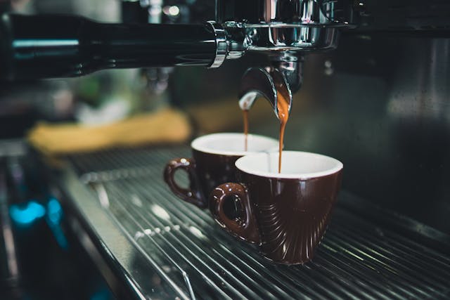 Photo of coffee dripping into a cup through a machine.