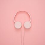 A photo of a pair of headphones against a pink background.