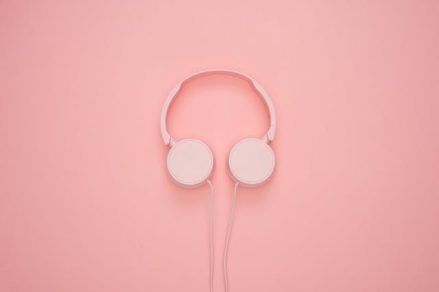 A photo of a pair of headphones against a pink background.