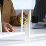 A hand plugging a wire to a router.