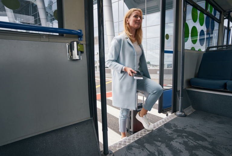 A lady entering an airport shuttle bus.