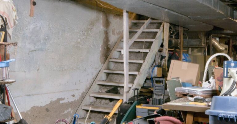 A basement with various items stored in it. There are old suitcases, boxes, and other items stacked on top of each other.